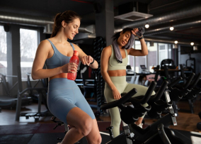Две девушка занимается спортом на велотренажерах